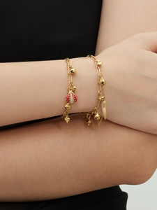Détail d'un bracelet double couche en or avec breloques cœur et coccinelle en acier