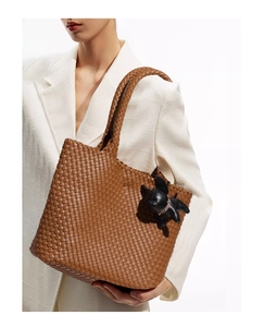 Detail of caramel brown woven leather tote with a stylish black bulldog bag charm