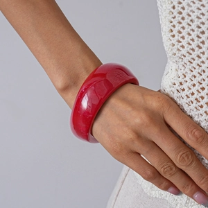 Close-up of a wide red translucent acrylic bangle on wrist with a minimalist design