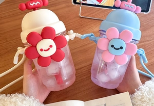 Close-up of cute cartoon sunflower plastic water bottles with straws and straps