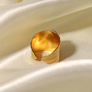 Detail of vintage golden leaf texture ring on beige silk background showing relief patterns