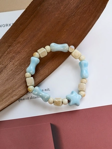 Close-up of ceramic beaded bracelet with bone and star shapes on a wooden background