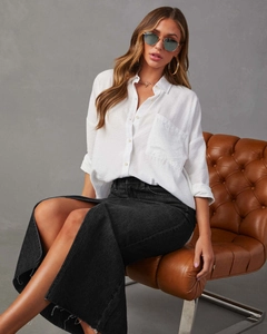 Dettaglio di una gonna lunga in denim nero con spacco alto e bordi grezzi sfilacciati
