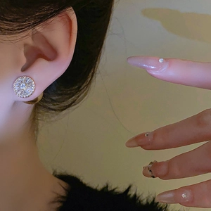 Gros plan d'une boucle d'oreille dorée avec zircons étincelants en motif solaire