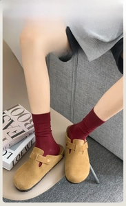 Detail shot of camel suede mule clogs with metal buckle paired with red knit crew socks