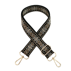Close-up of ethnic geometric pattern strap with golden metal hooks and adjustable buckle