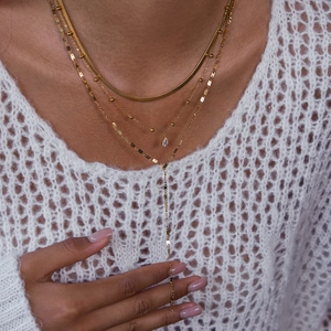 Detail of 18K gold stainless steel layered necklaces featuring a teardrop zircon pendant