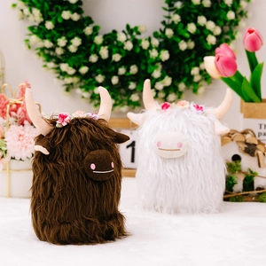 Close-up of Highland Cow plush toys with floral crowns in a cozy lifestyle setting