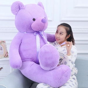Detail of large purple teddy bear with silk bow held by a model for size perspective
