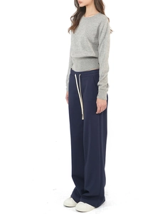 Side view of woman in dark blue wide leg drawstring sweatpants and grey knit top