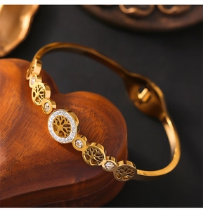 Close-up of gold hollow tree of life bracelet with rhinestones on wooden stand