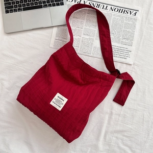 Detail of red corduroy tote bag showing striped texture and white brand patch on bed
