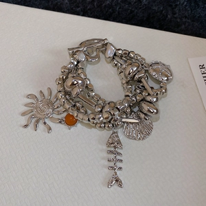 Detailed close-up of multilayer silver beaded bracelet with sun, shell and starfish charms