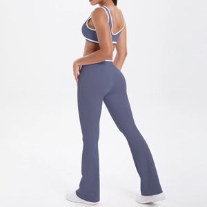Detail view of flared yoga pants and racerback sports bra in grey blue with white piping