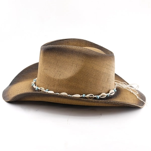 Macro detail of bohemian straw hat with seashell beads and vintage gradient brim