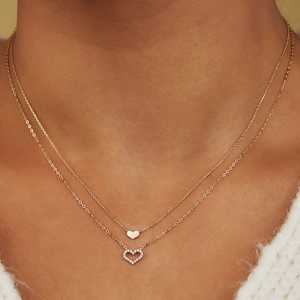 Close-up of double-layer necklace with solid and hollow heart pendants on neck