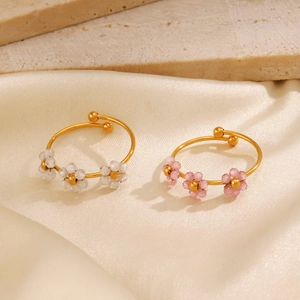 Adjustable gold stainless steel flower rings with pink and white petals on satin backdrop