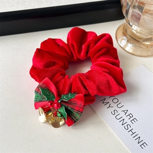 Detail of Christmas scrunchie with red bow, holly berries and gold bells for hair accessories