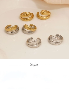 Flat lay of minimalist double-layer ear cuffs in gold and silver on a silk background