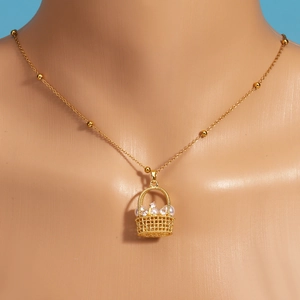 Gros plan du pendentif panier de fleurs avec perles et pierres sur collier doré