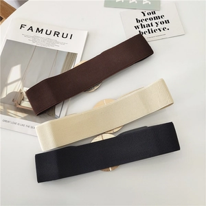 Detailed view of elastic waist belts in brown, beige, and black with round gold buckles