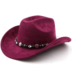 Détail d'un chapeau de cow-boy avec ruban bohème, breloque Hamsa et perles turquoise