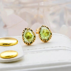 Macro shot of olive green teardrop gem stud earrings with gold plating and prong setting