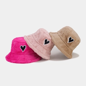 Drei Plüsch-Fischerhüte in Rosé, Rosa und Khaki mit schwarzen Herz-Patches im Detail