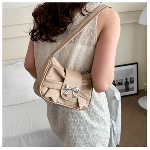 Borsa sottobraccio beige con fiocco metallico indossata dalla modella vista dietro