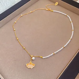 Elegant gold plated necklace with ginkgo leaf pendant and white pearls on velvet tray