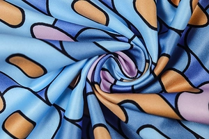 Macro detail of geometric print satin fabric with blue and orange shapes and silky texture