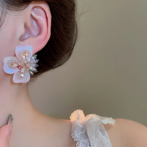 Detail of floral earring with pink petals and crystal beads on a model's ear