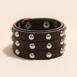 Detailed macro shot of brown leather wristband with triple row silver metal rivets
