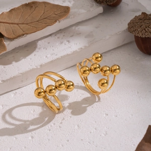 Close-up of gold geometric beaded ring on white stone with autumn leaves and acorns