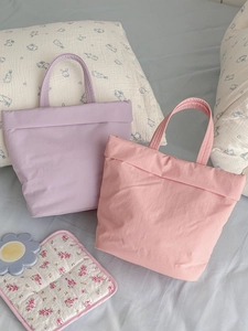Minimalist macaron padded tote bags in lavender and pink displayed on a cozy bed
