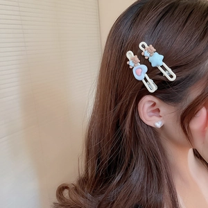 Gros plan de barrettes ours et étoile avec boucle d'oreille cœur sur un modèle