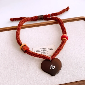 Detail of plush heart pendant necklace with metal cross and woven brown rope strap