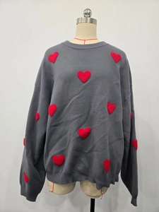 Detail of grey knitted sweater featuring red heart patches and round neckline texture