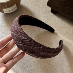 Detail of dark brown fabric headband with white wave embroidery and twill texture