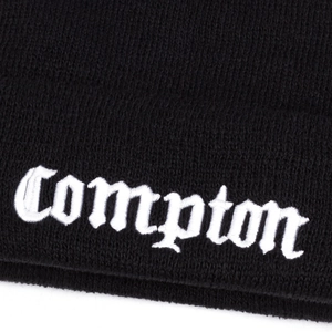 Detailed close-up of white Compton Gothic embroidery on a black ribbed knit beanie hat