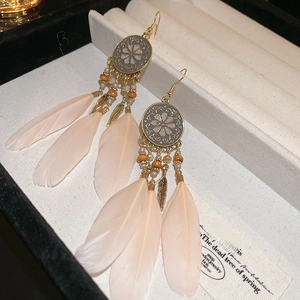 Detail shot of bohemian pink feather earrings with golden beads and hollow metal discs