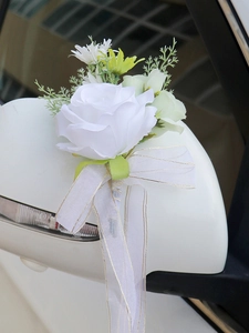 Close-up of white artificial rose with gold-edged organza ribbon on car rearview mirror