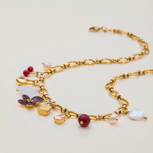 Makroaufnahme des 18K vergoldeten Armbands mit lila Emaille-Blume und rosa Herzstein