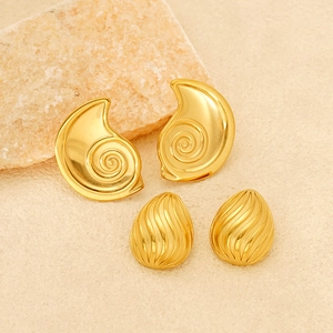 Golden sea shell and teardrop earrings with textured finish on stone background