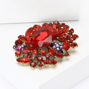 Makroaufnahme einer eleganten Goldbrosche mit großem rotem ovalem Edelstein und Strass