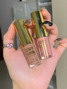 Close-up of matte nude and coral liquid eyeshadow bottles with golden caps held by hand