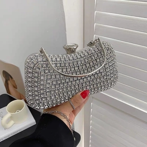 Detailed close-up of a silver evening clutch bag featuring a large rhinestone buckle and chain