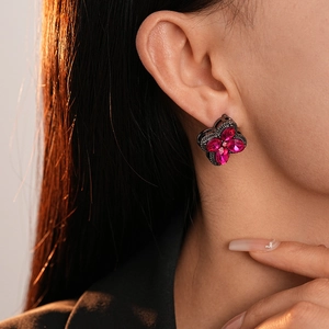 Close-up of elegant four-petal flower earrings with pink gems on a female model
