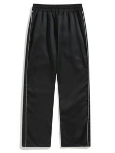 Detail of elastic drawstring waistband and white side stripes on black woven trousers
