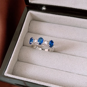 Détail d'une bague ajourée argentée avec trois gemmes bleues ovales et zircons